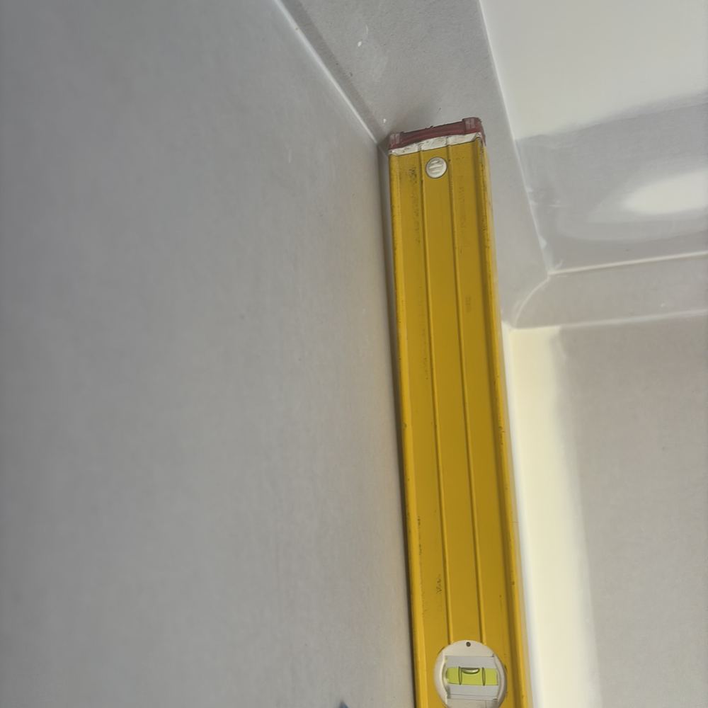 Plastered wall bowing beyond the tolerance for a flat surface, found during a fixing inspection in Sunbury