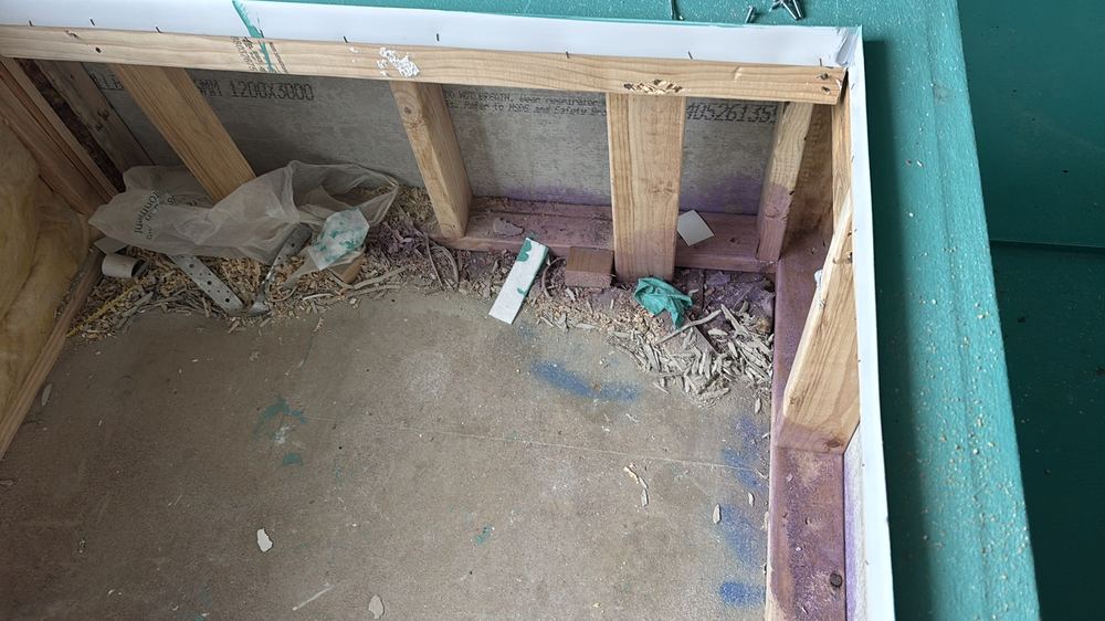Water and debris left sitting in the bath hob cavity, found during a waterproofing inspection in Reservoir